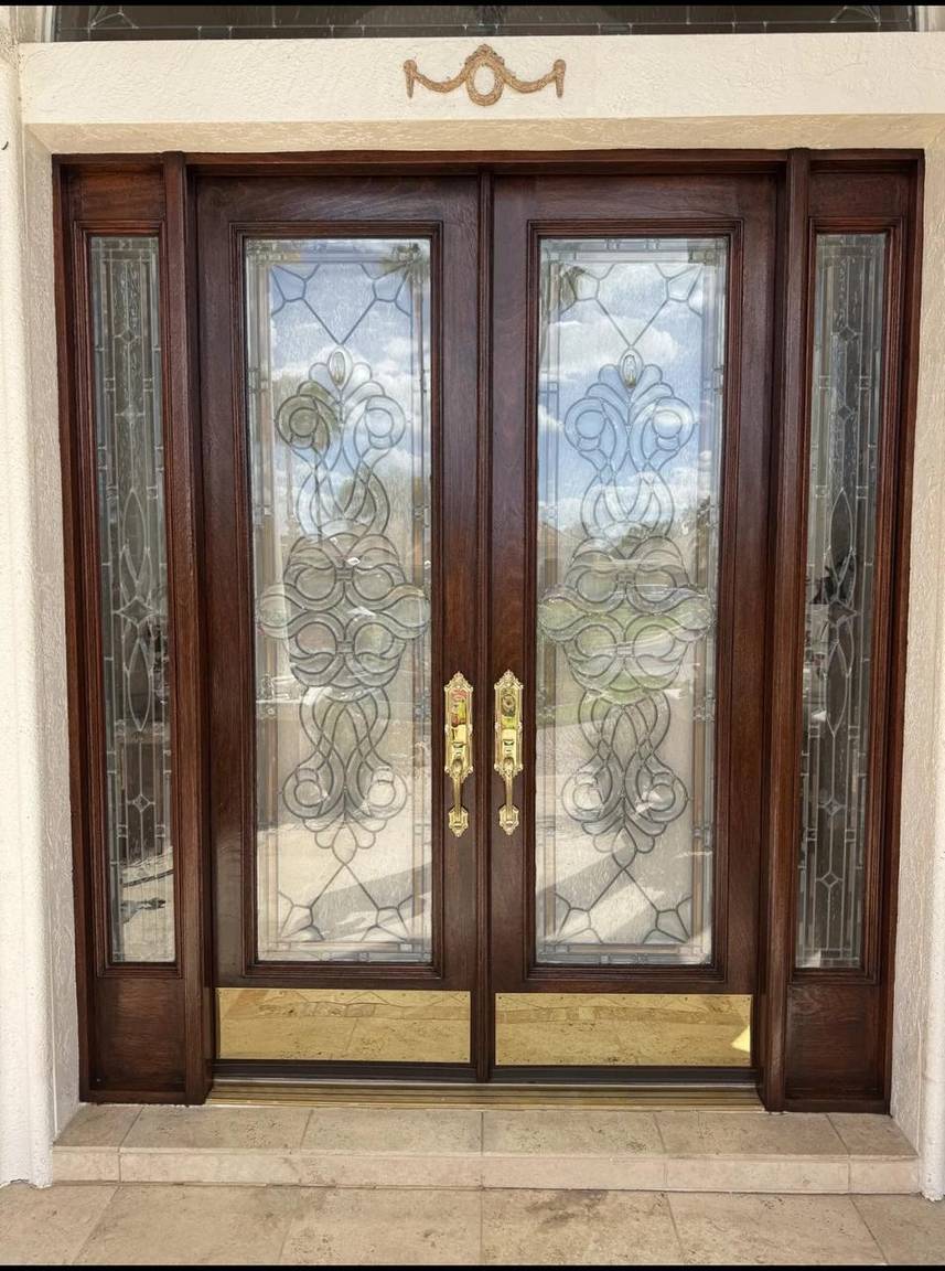 Finished double entry doors after restoration, dark stained wood with decorative glass panels