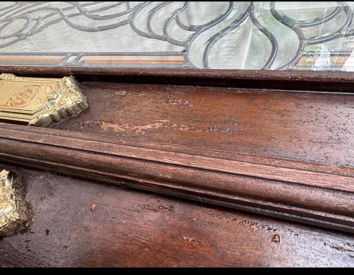 Close-up of peeling, damaged finish on the entry door before restoration