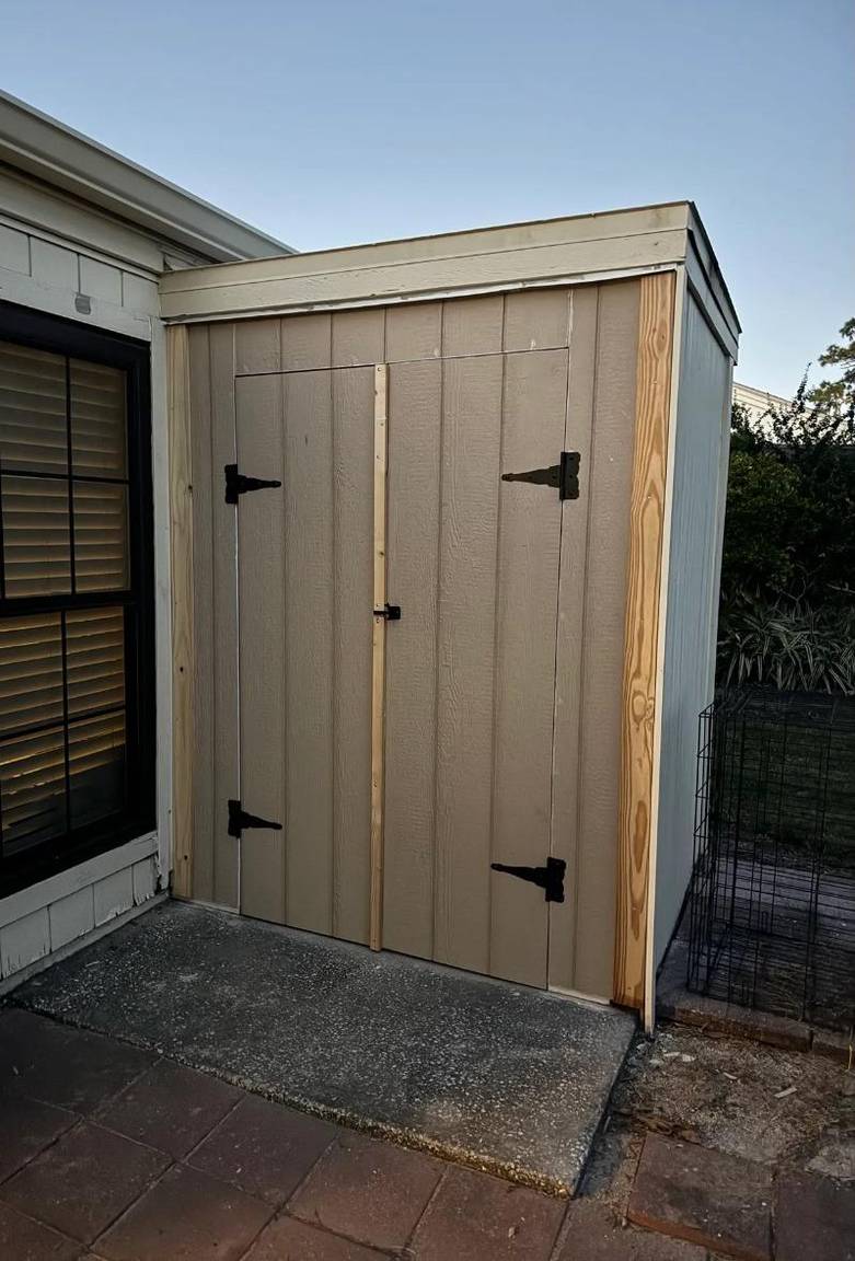 New outdoor storage doors installed with fresh trim and black hinges