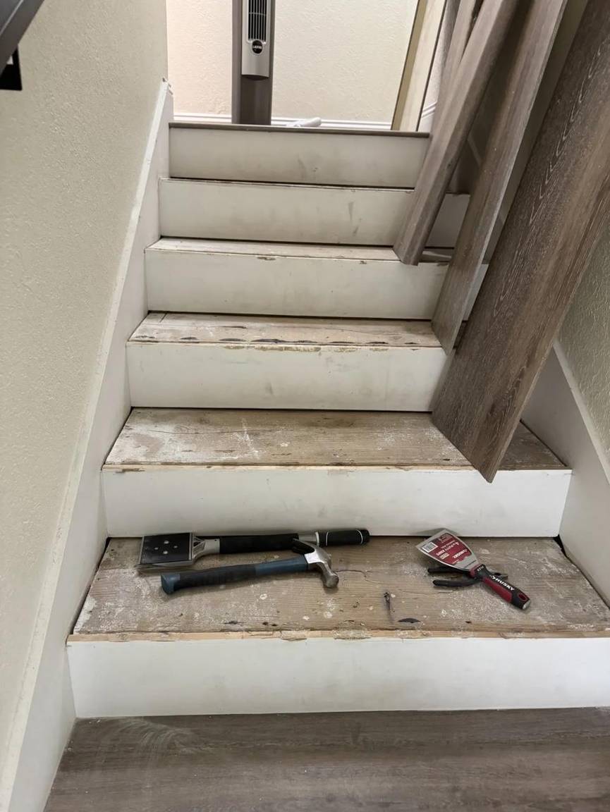 Staircase stripped and prepped before luxury vinyl installation, tools on the steps